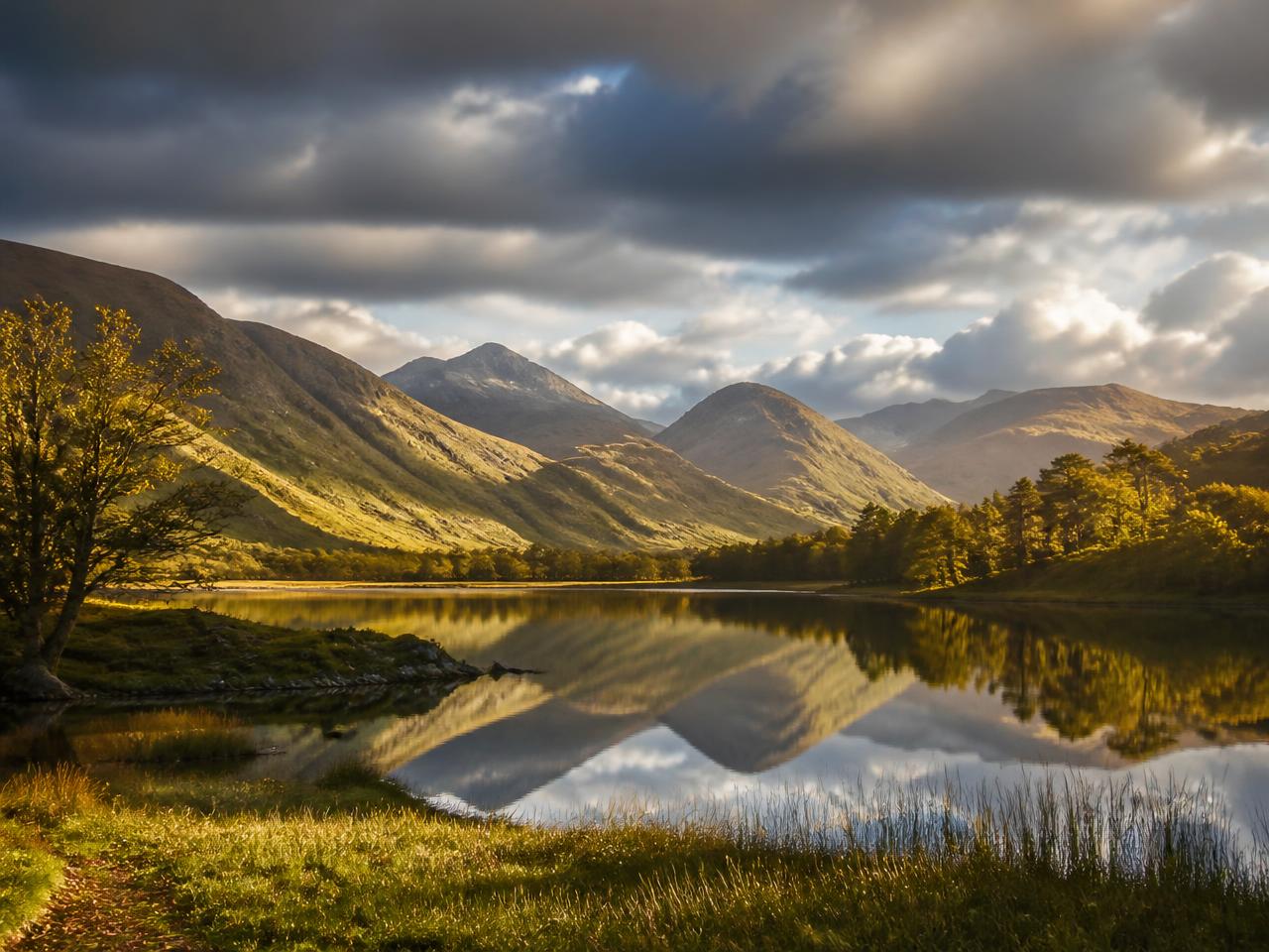 Sunlit Lake District fells reflected in a still Cumbrian lake, the landscape near JEL Marketing's Carlisle base